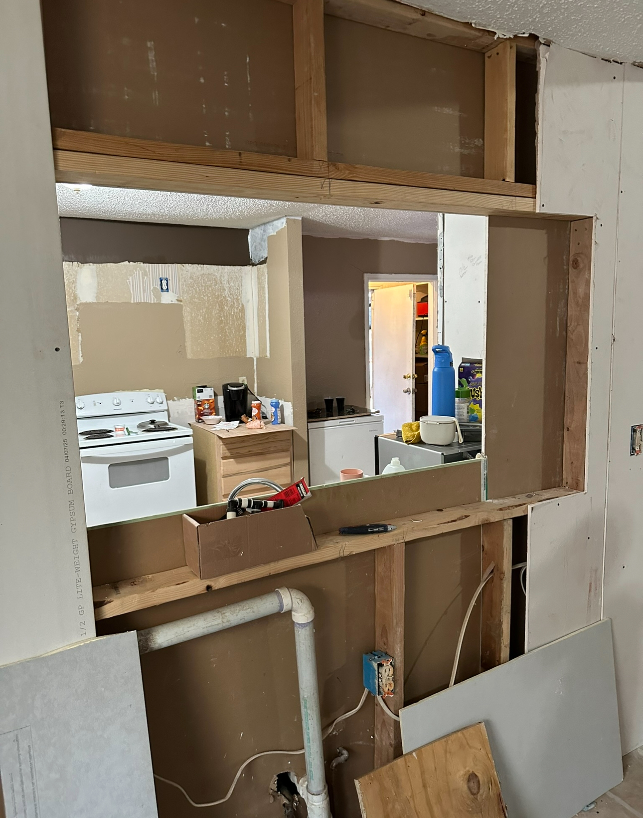 Kitchen wall opening with exposed studs prepped for drywall install
